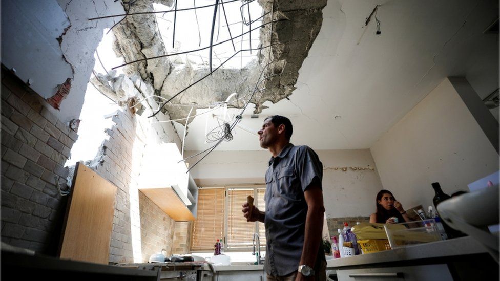 Мужчина в Ашкелоне смотрит на ущерб, нанесенный его дому ракетой, выпущенной из Газы