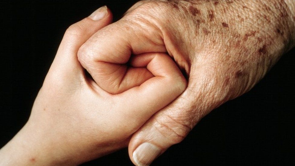 Young person and elderly person holding hands