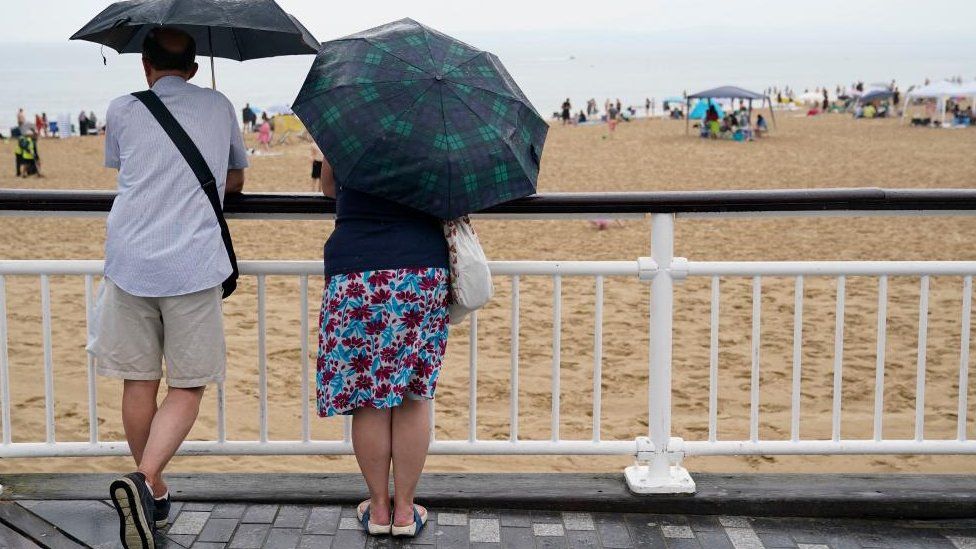 People sheltering under umbrellas at Bournemouth beach