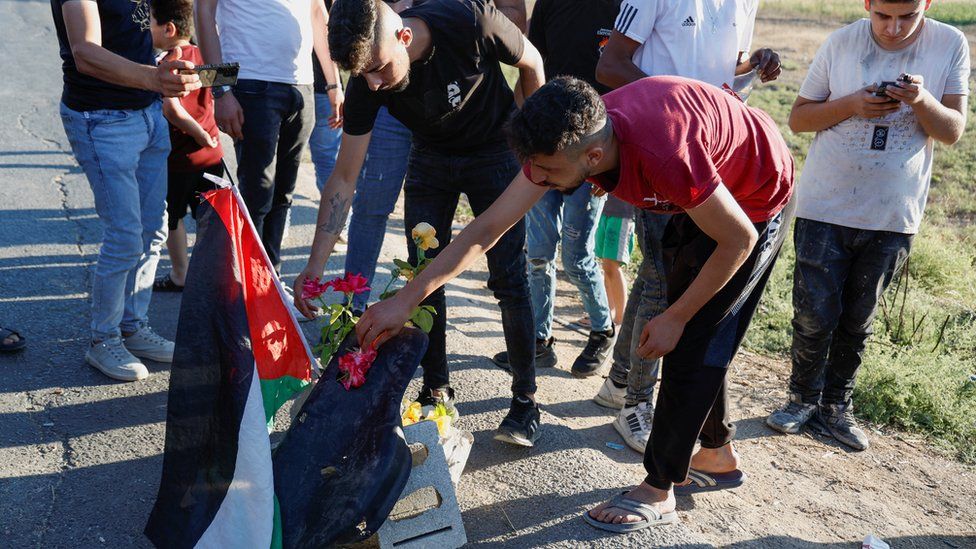 Palestinians gather at the scene where Israeli forces targeted a car and killing three Palestinians near Jenin in the Israeli-occupied West Bank, 6 August 2023