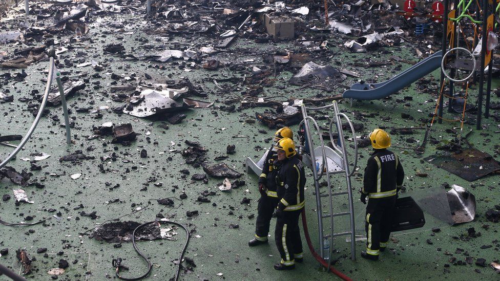 Firefighters stand amid debris in a childrens playground