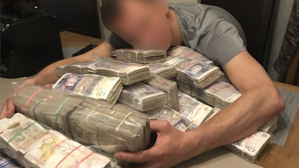 A man hugs a pile of cash