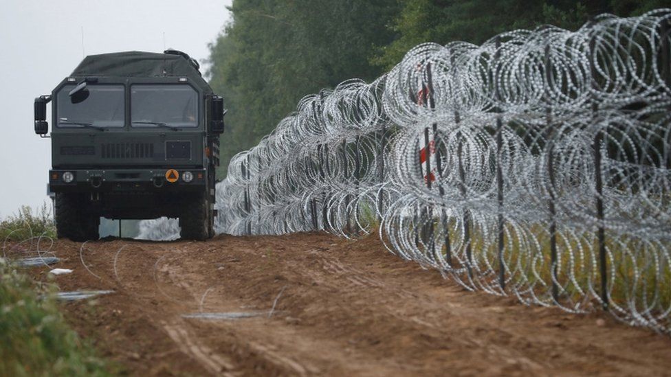 A view of a vehicle next to a fence built by Polish soldiers on the border between Poland and Belarus