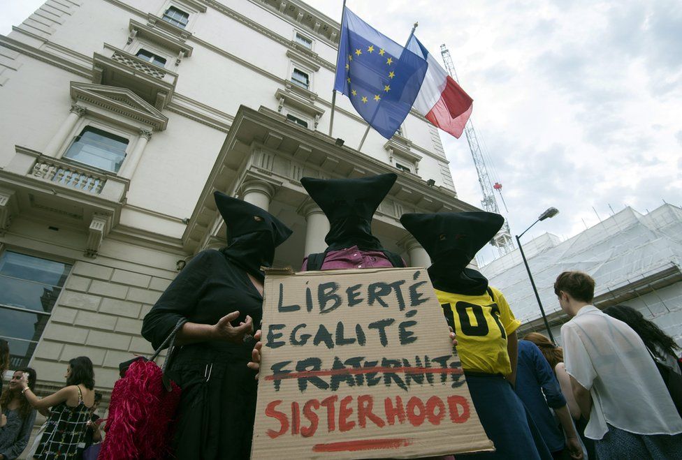 Women carrying sign reading liberte egalite fraternite but the fraternite is crossed out and replaced with sisterhood