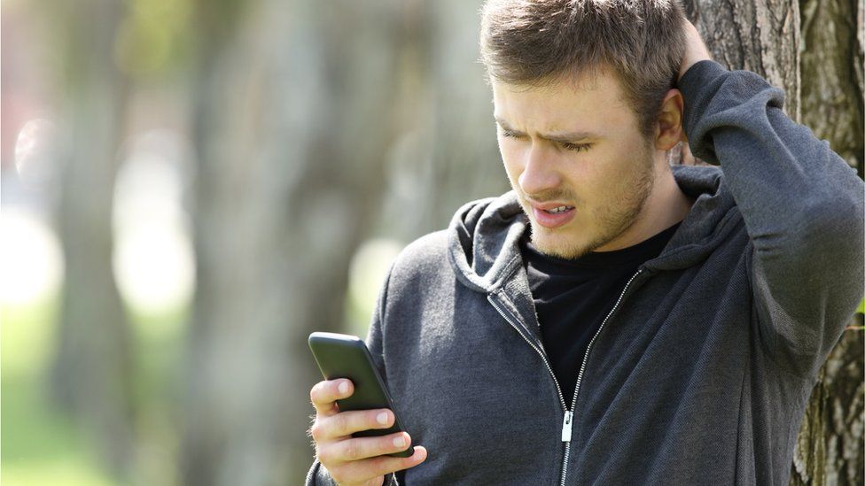 Man looking at his phone with a frustrated expression