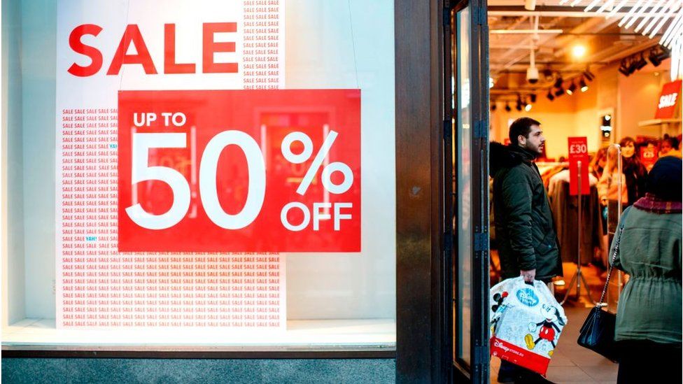 A woman is seen walking past a large SALE sign at H&M store on London'  Oxford Street. Last minute Christmas shoppers take advantage of  pre-Christmas bargains at Oxford Street in London. Fewer