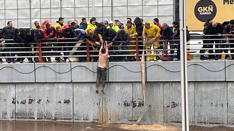 A man trapped in the Abide Koprulu junction, which was flooded due to the downpour that had been effective since yesterday evening, is being rescued in Sanliurfa