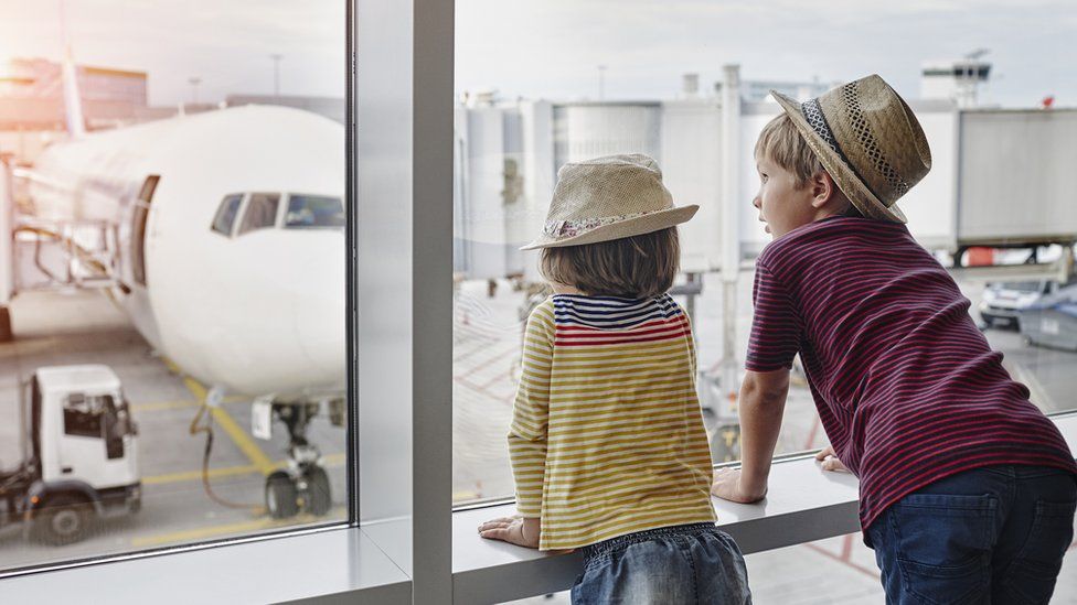 Children looking out of an airport window.