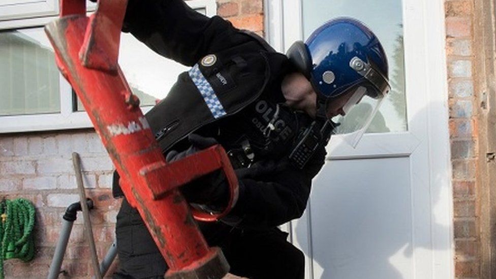 Police officer knocks down door