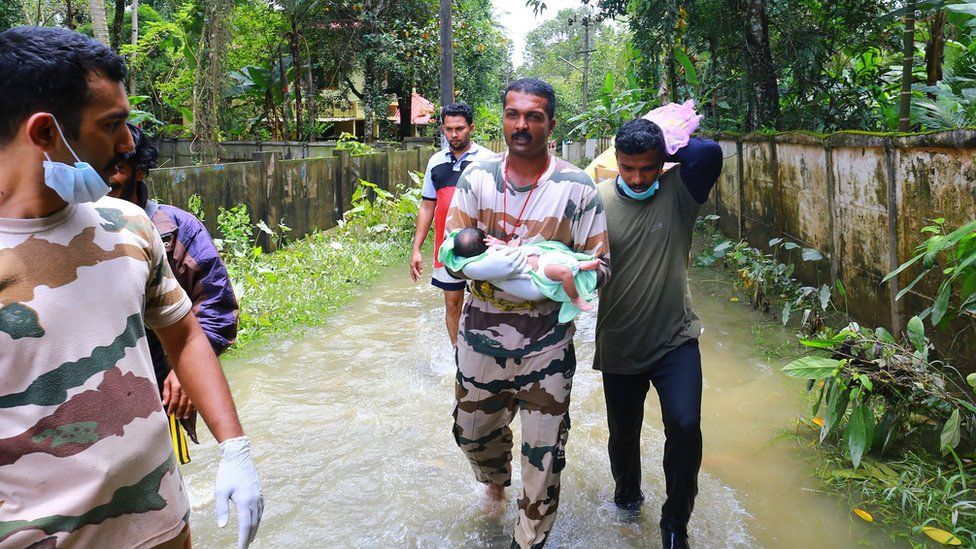 A worker carries a baby boy rescued with his family in Chengannur following widespread flooding in the south Indian state of Kerala on August 20, 2018