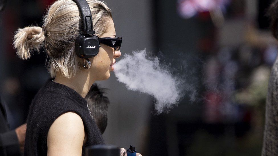 A woman uses a single-use vaping product in London