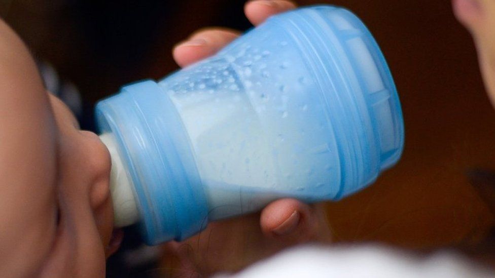 A baby drinks milk from a bottle