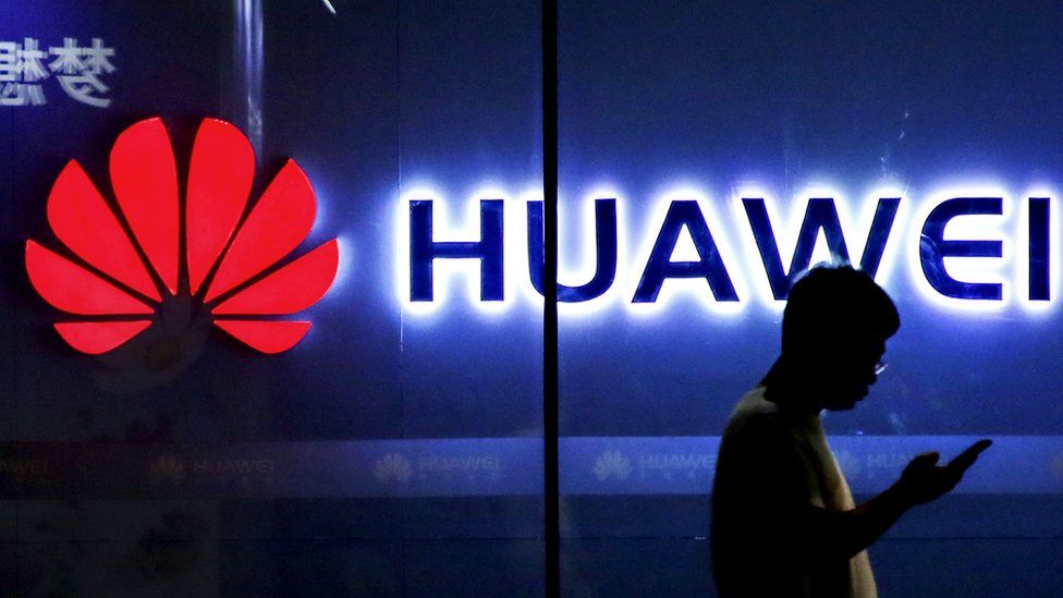 Man walks in front of Huawei sign