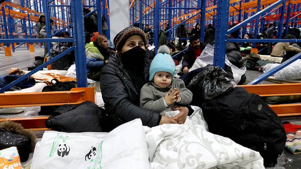 A woman holds a child in a temporary centre for migrants in Belarus