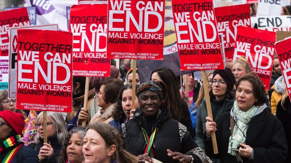 Women hold placards as they take part in Million Women Rise ahead of International Women's Day in 2022
