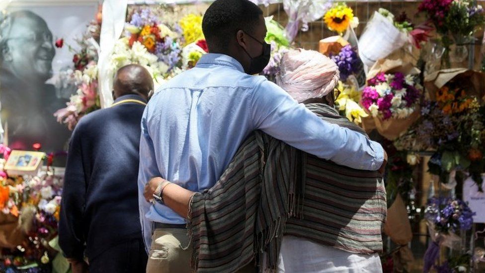 Relatives of Desmond Tutu embrace at a remembrance wall