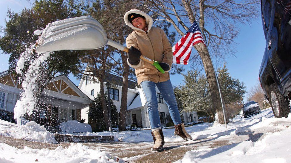 A resident shovels snow from outside her home after a storm February 15, 2021 in Fort Worth, Texas