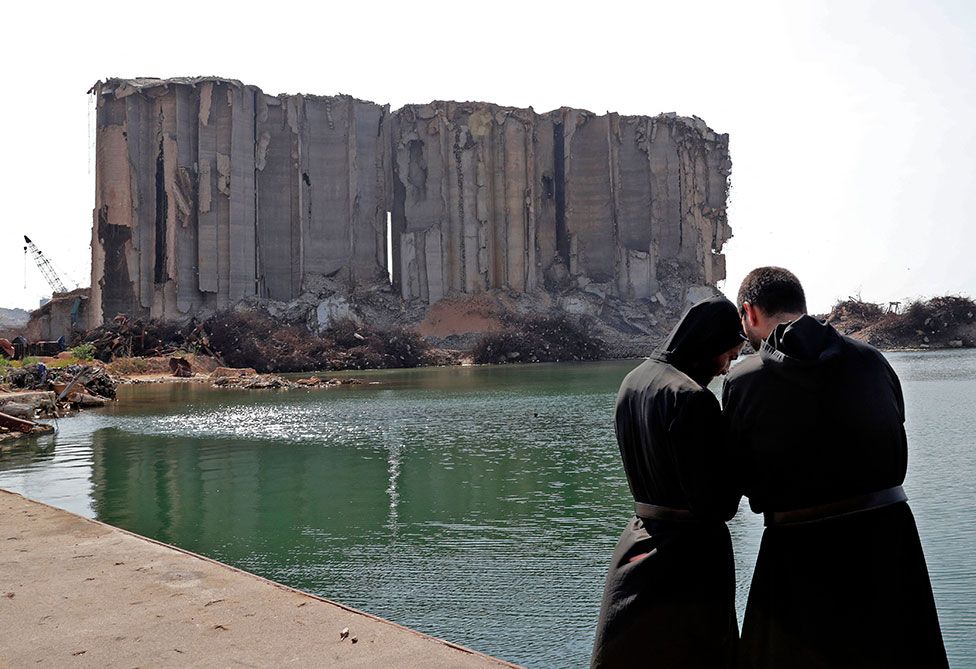 Maronite clergymen pray near damaged grain silos at the port of Lebanon's capital on the first anniversary of the explosion that ravaged the port and the city
