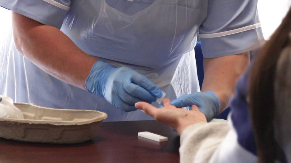 Healthcare worker performing finger-prick test on patient