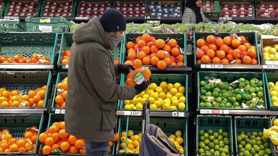 Мужчина смотрит на фрукты в супермаркете Tesco