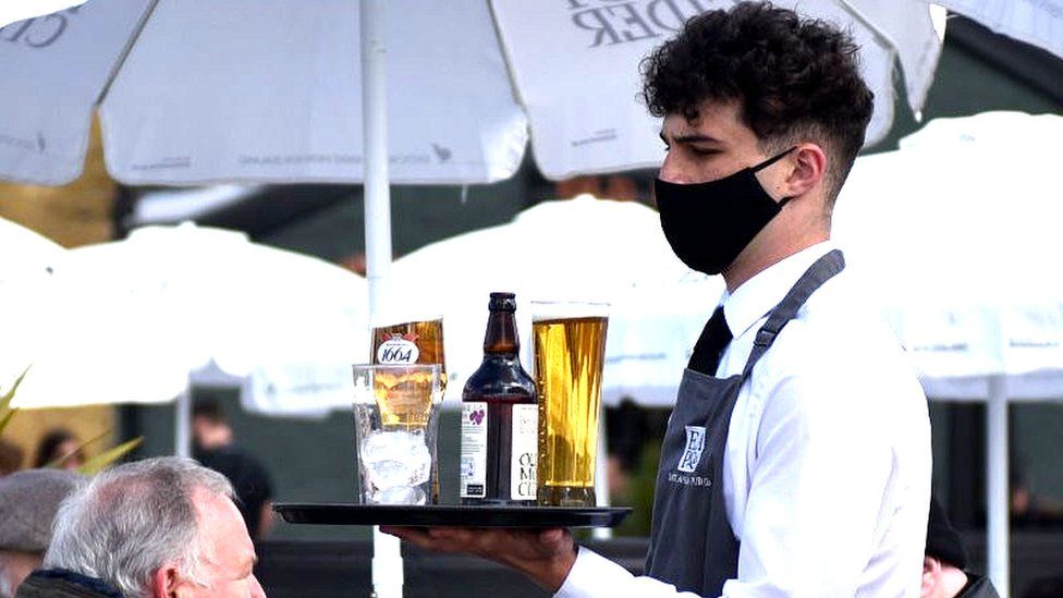 Waiter in mask serves drinks
