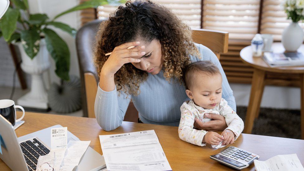 Mum looks at bills with a baby on her lap