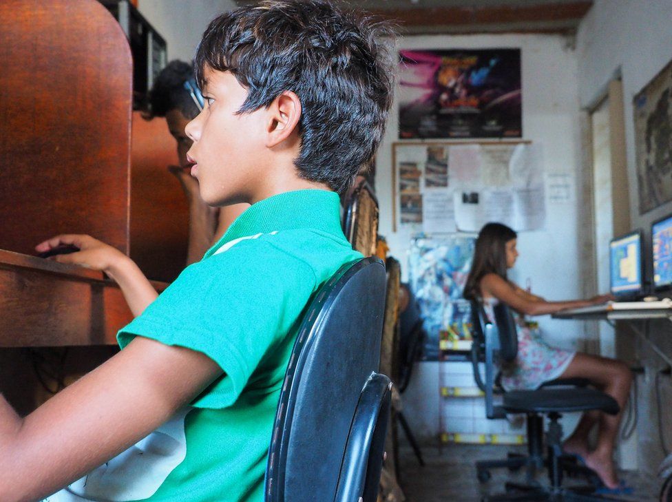 Brazil, 2015. A boy sits in an internet cafe.