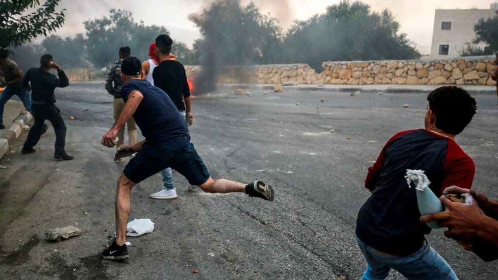 Palestinian protesters throw stones at Israeli security forces during clashes in the village of Kobar, west of Ramallah