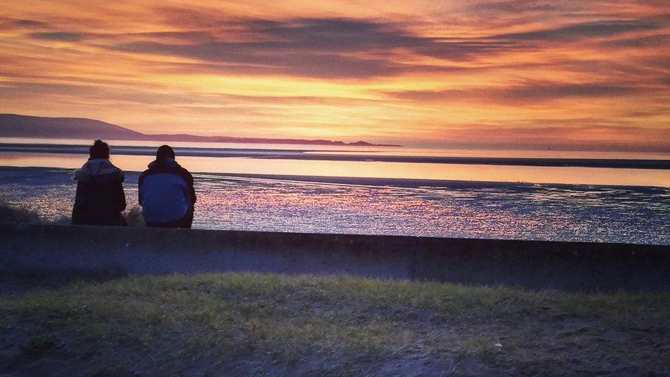 A couple watching the sunset in Llanelli