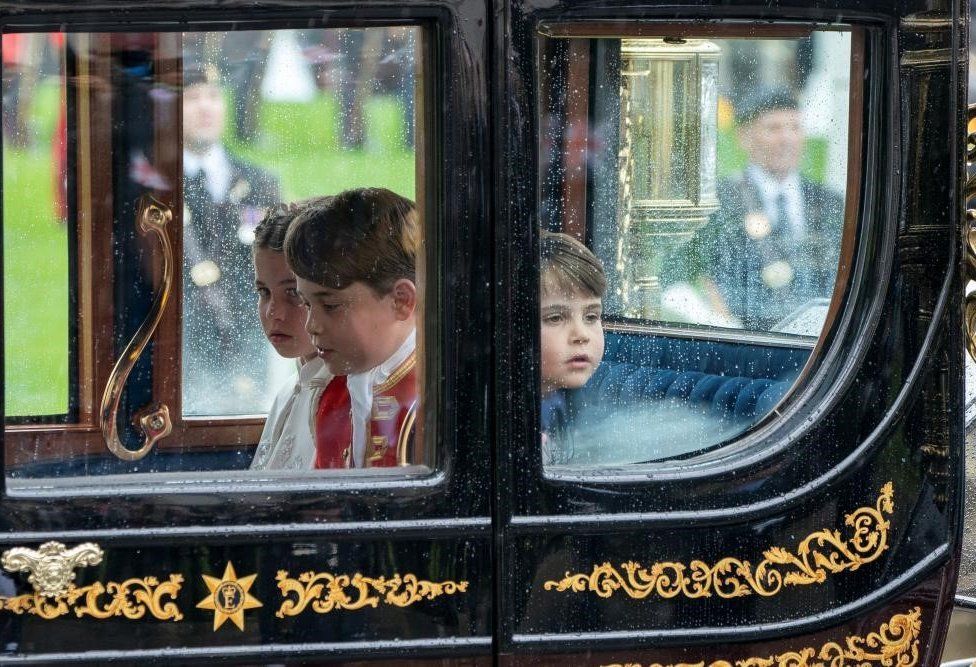 Prince Louis with his brother Prince George and sister Princess Charlotte waving from a carriage as they leave the Coronation