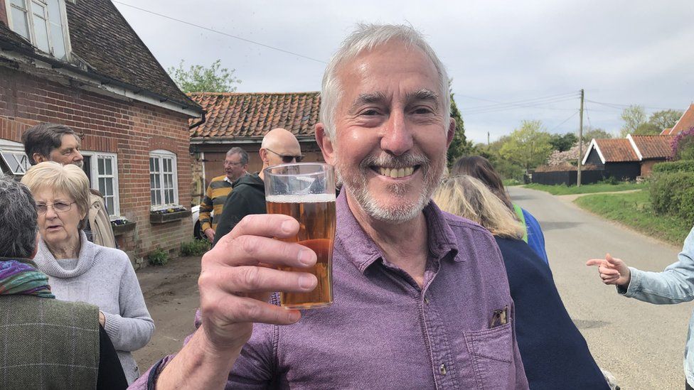 Brian Cox raising a pint of beer