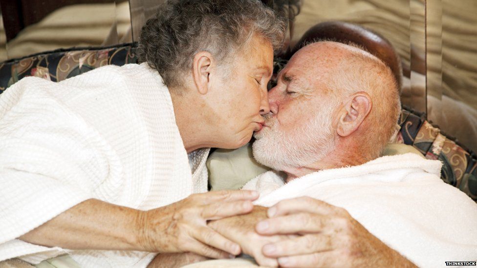 Elderly people kissing in bed
