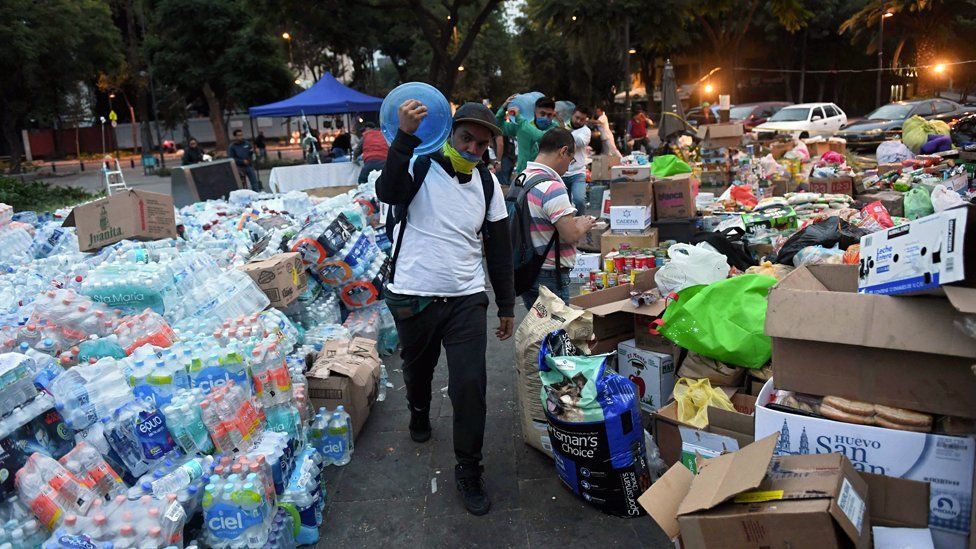 A man walks through piles of food and water bottles