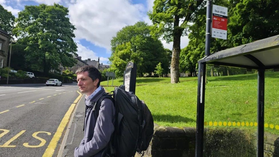 Man with backpack waiting at a rural bus stop