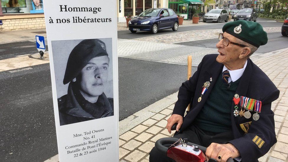 Ted at Pont L’Eveque looking at an old photo of himself where he is described as one of the town’s liberators