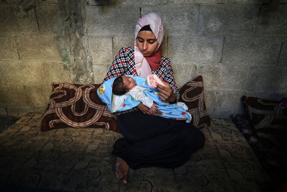 A Palestinian mother fans her child inside a tent at a camp for displaced people in Deir al-Balah in the central Gaza Strip