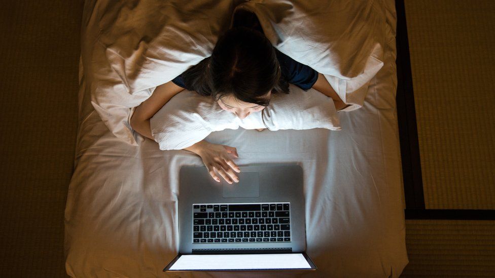 person on laptop in bed