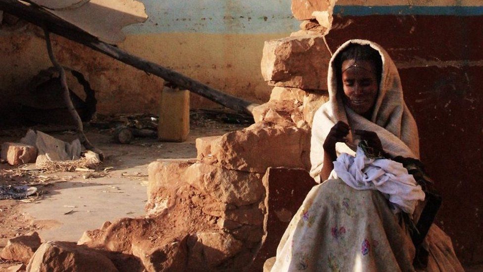 An Ethiopian woman stands by in front of ruins in the Ethiopian town of Zala Ambesa, 20 February 2001, devastated by the war between Ethiopia and Eritrea