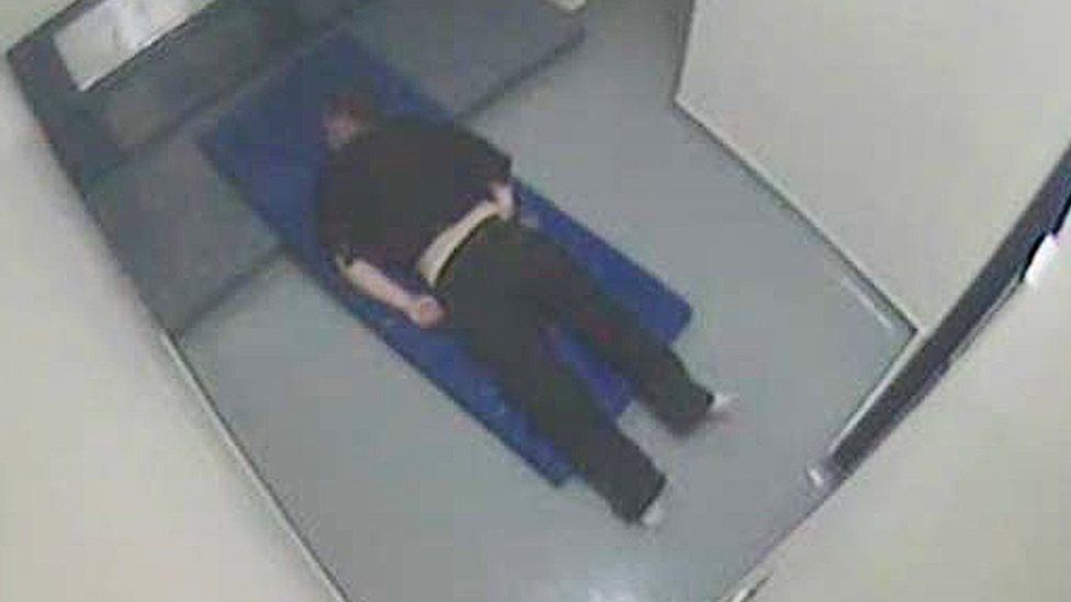 Thomas Orchard handcuffed and lying face down on a mattress in his cell