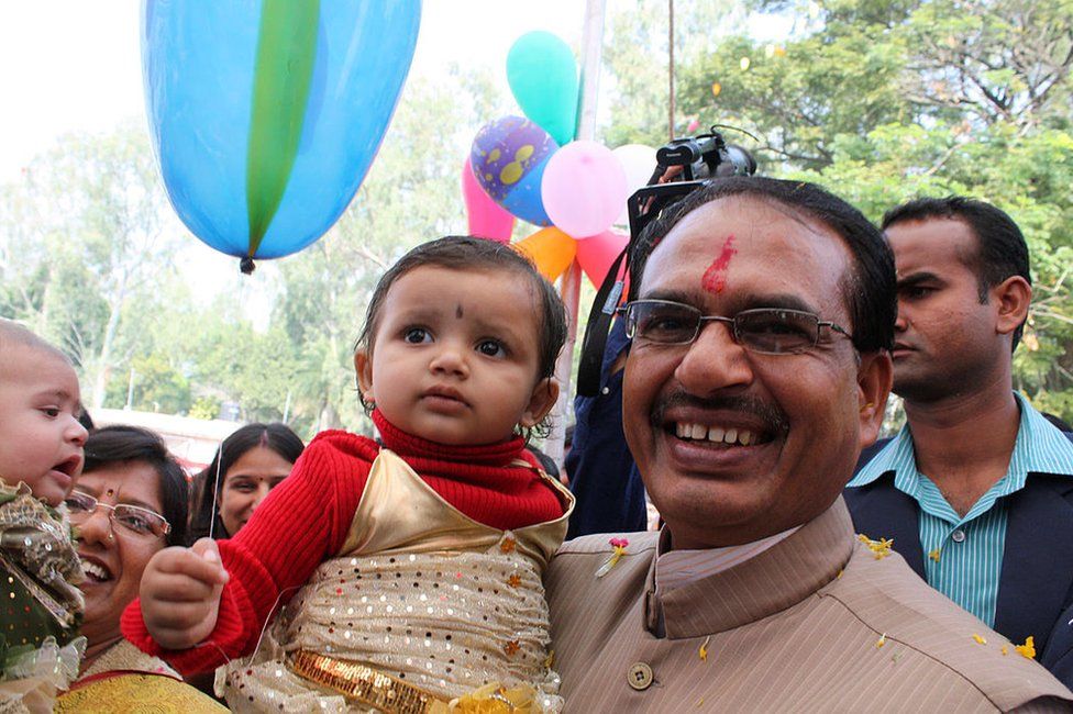In this photograph taken on October 5, 2011, Chief Minister for the central Indian state of Madhya Pradesh Shivraj Singh Chouhan (R) poses with a child at a function to honour the 'girl child' in Bhopal