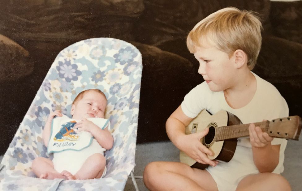 Robyn as a baby with her older brother Gareth serenading her on his guitar