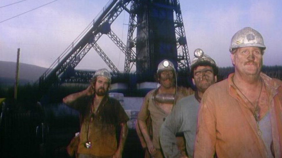 Old picture of four miners with coal-covered faces
