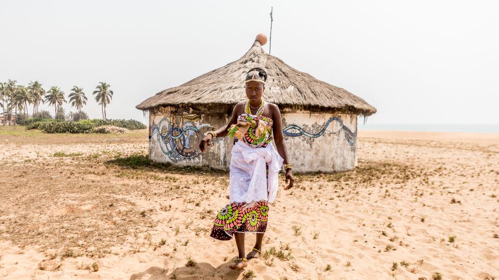 Voodoo follower leaves a hut after completing a Voodoo ritual during the Voodoo Festival in Ouidah, Benin, on January 10, 2022.