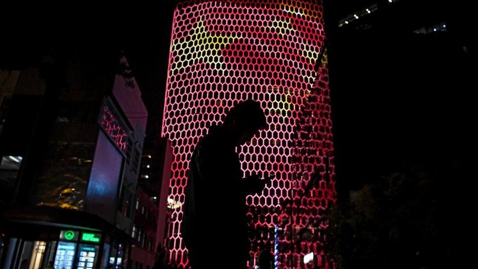 Person on smart phone in front of Chinese flag projection