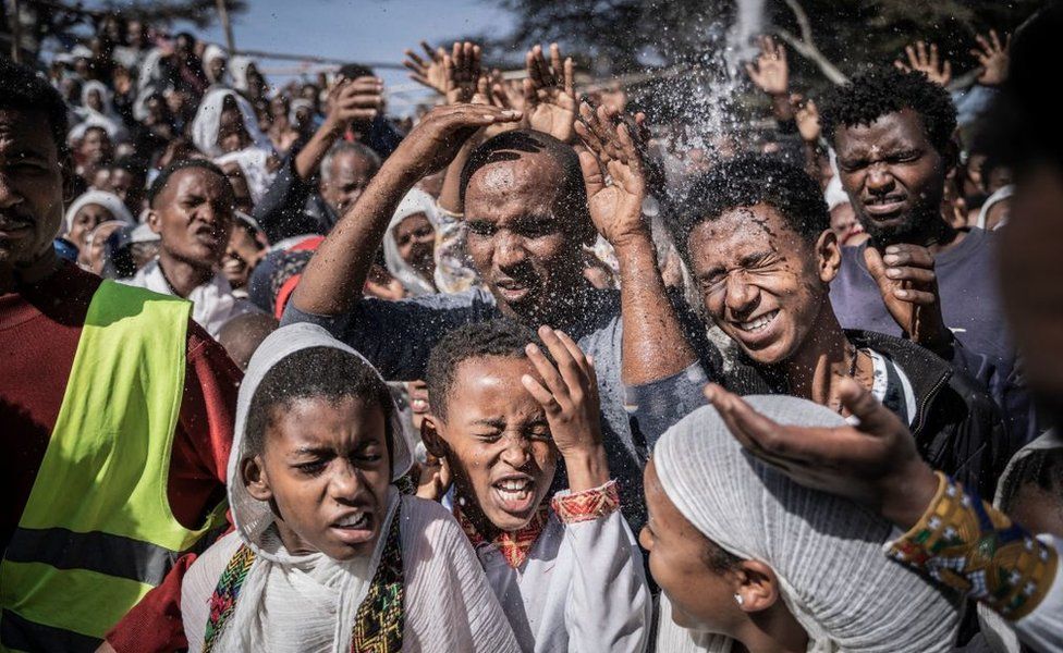 Ethiopian Orthodox worshippers get holy water sprayed on their faces during the celebration of the Ethiopian Epiphany on lake Ziway, also known as lake Dembel, Ethiopia, on January 19, 2023