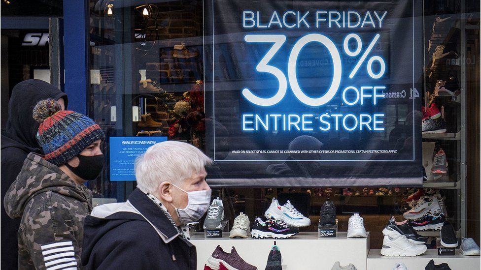 man outside store offering Black Friday discount