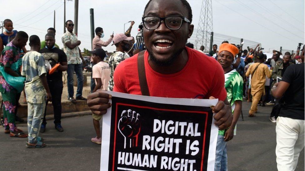 Мужчина несет плакат во время демонстрации в Охоте в Лагосе 12 июня 2021 года, когда нигерийские активисты призвали к общенациональным протестам по поводу того, что они критикуют как плохое управление и небезопасность, а также недавнего запрета правительством США социальной сети Twitter. президента Мухаммаду Бухари.