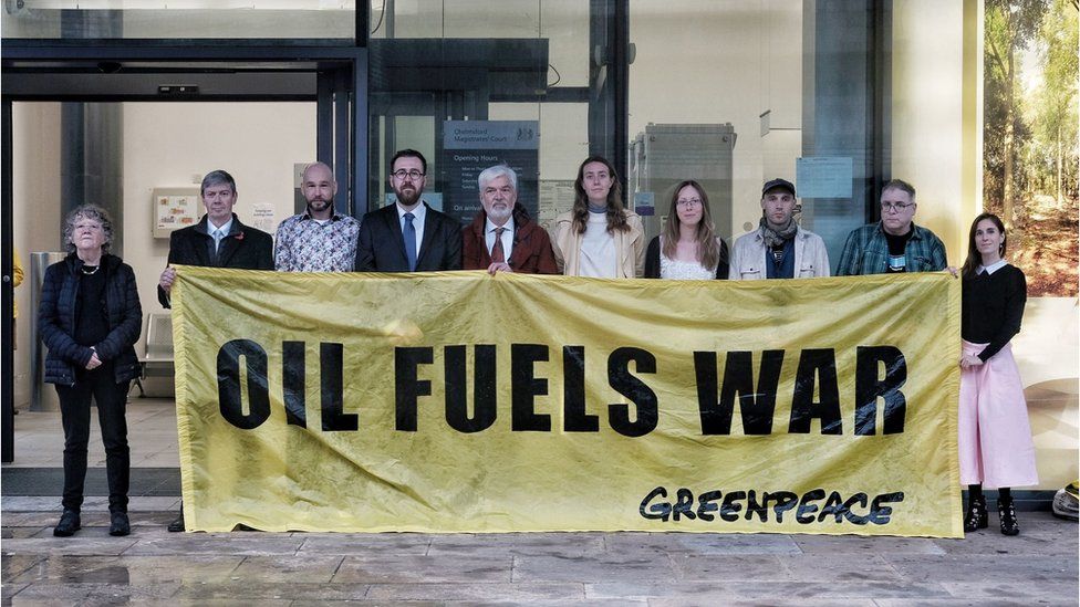 Greenpeace activists with banner that reads foil fuels war