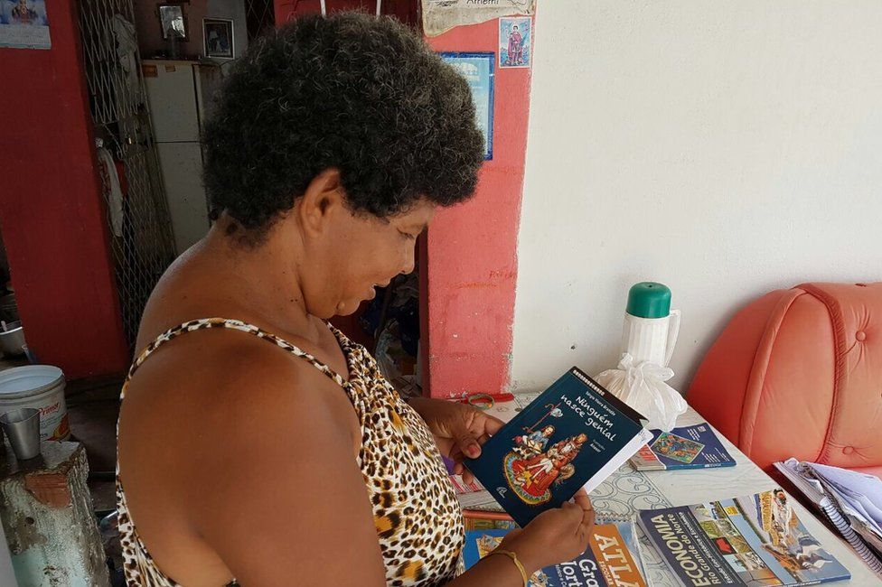 Sandra Maria de Andrade holds up a book