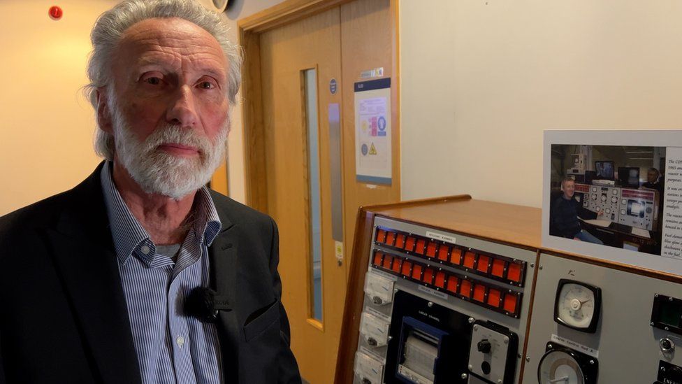Trevor Chambers, the former head of the reactor centre, stands next to the original control panel